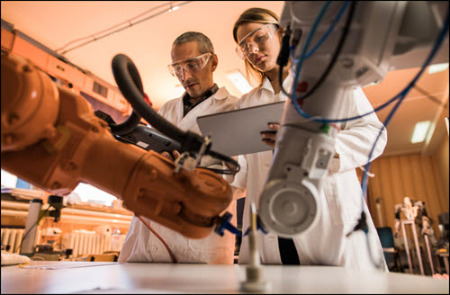 Technicians cooperating while working on robotic arm